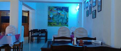 Un comedor con mesas y sillas, un cuadro en la pared y una placa en la mesa.