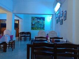A dining area with tables and chairs, a painting on the wall, and a nameplate on the table.