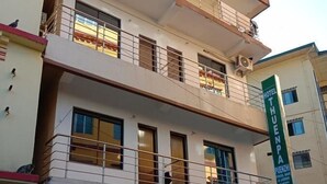Un hôtel à plusieurs étages, doté de balcons, d’une enseigne verte et d’une entrée abritée.