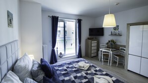 A modern bedroom with a bed, a desk, and a TV. - Baltic-Apartments - Aquamarina C12 (Swinoujscie)