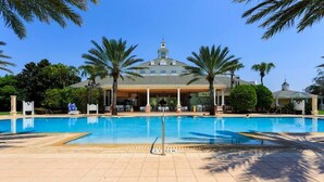 A large swimming pool with a tiled deck, palm trees, and a building with a dome roof in the background. - Reunion Resort Townhome - minutes from Disney! (Reunion)