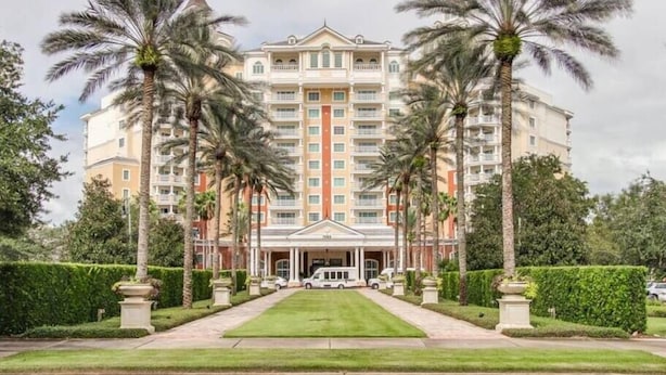 A multi-story hotel with a central entrance, surrounded by palm trees and a well-maintained lawn. - Reunion Resort Townhome - minutes from Disney! (Reunion)