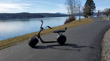 Een stilstaande elektrische scooter op een verhard pad langs een meer.
