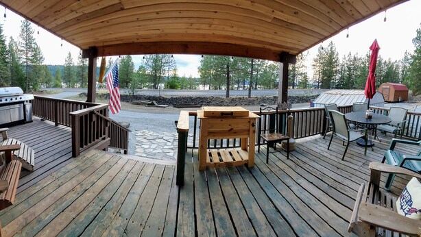 Une terrasse en bois avec des sièges d’extérieur, un drapeau américain et un barbecue.