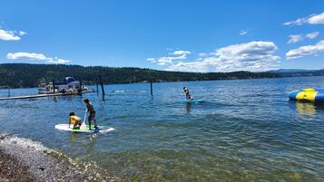 A lake with clear water, a dock, and a forested hillside in the background.
