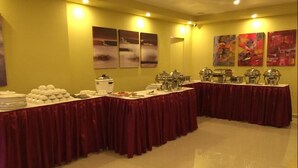 A buffet setup with multiple tables covered in red tablecloths, featuring various food service items and a coffee station. - Le Raj Courtyard (Gummidipundi)
