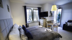 Een moderne hotelkamer met een groot bed, een bureau, een televisie en een balkon met uitzicht.