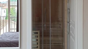 A room with a built-in shower enclosure, a bed, and a window overlooking a balcony. - B&B Il Tiglio (Lucca)