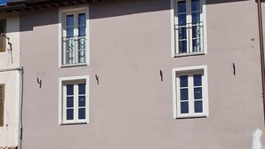 A two-story building with white-framed windows, a flat roof, and a brick-paved entrance area with potted plants. - B&B Il Tiglio (Lucca)