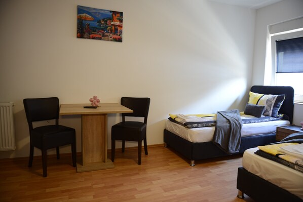 A bedroom with a bed, two chairs, a small table, and a painting on the wall.