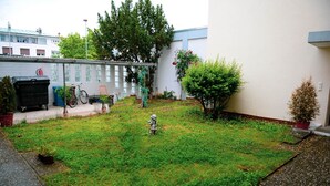 A small, grassy courtyard with a statue, a bicycle, and a fire hydrant. - Pension und Monteurzimmer VICTORIA (Ludwigshafen)