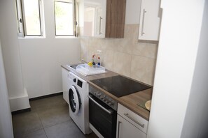 A compact kitchen with a washing machine, oven, and a small countertop.