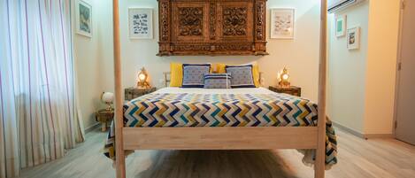 A bedroom with a wooden four-poster bed, a globe on a side table, and framed pictures on the wall.
