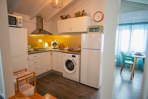 Une petite cuisine équipée d’un lave-linge, d’un four à micro-ondes et d’une horloge murale.