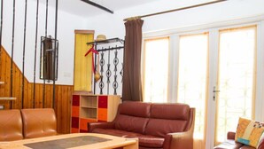 A living room with a brown leather sofa, a wooden coffee table, and a red and orange storage unit.