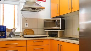 A kitchen with orange cabinets, a stainless steel microwave, a coffee maker, and a toaster.