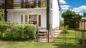 A two-story building with a balcony, a gated entrance, and a small garden area.