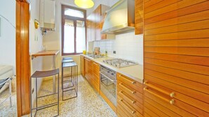 A modern kitchen with wooden cabinets, a gas stove, and a window providing natural light. - DolceVita Apartments N. 331 (Venice)