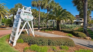 A sign for Seacrest Beach with a white picket fence and palm trees in the background. - Prime Beach Location with Stunning Resort Pool! (Seacrest Beach)