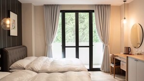 Un dormitorio con una cama, un escritorio y un ventanal con cortinas.