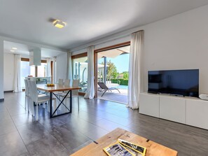 Relax in this spacious living area with a large flat-screen TV, dining table, and pool views.