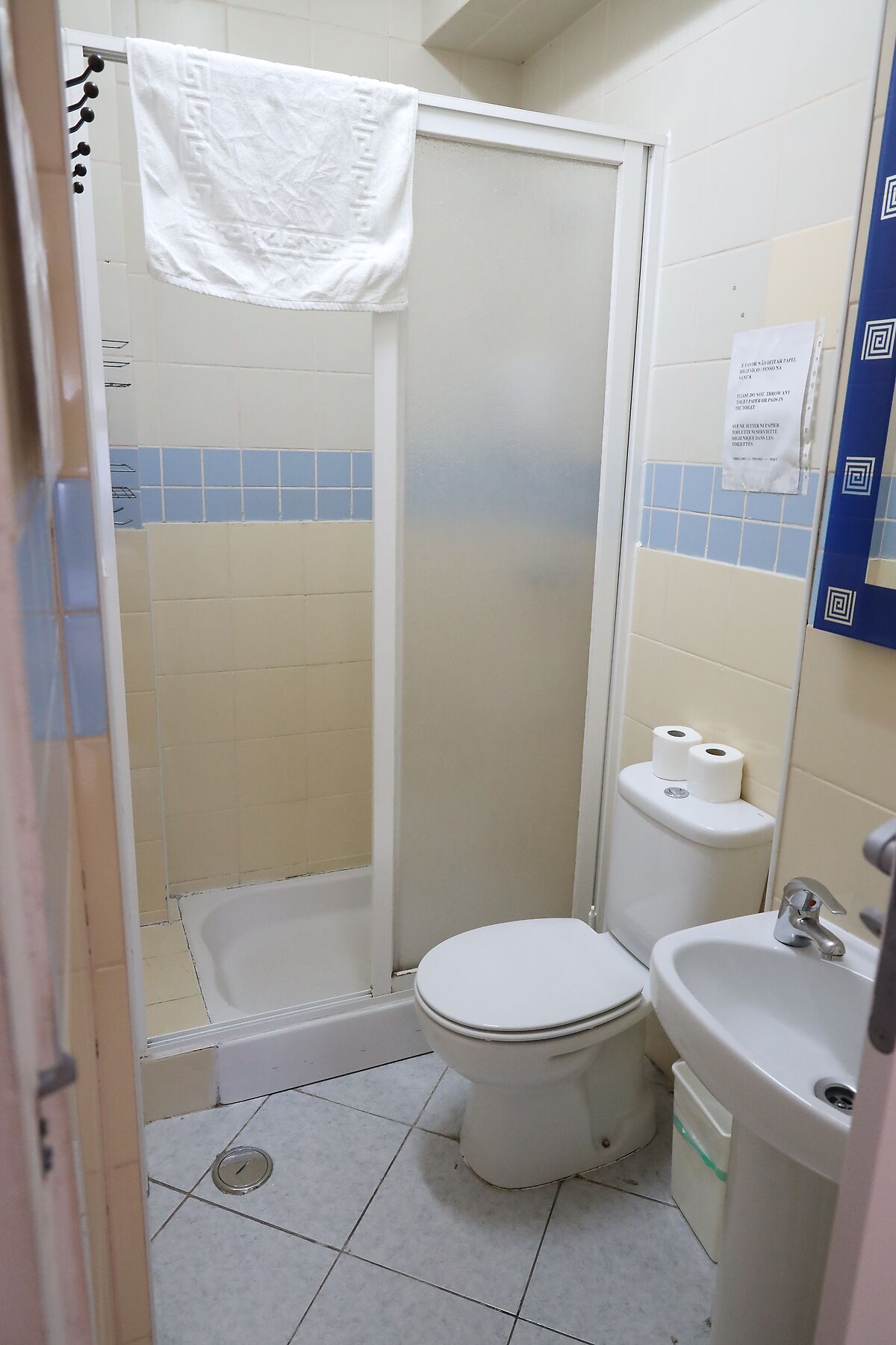 A small, compact bathroom with a toilet, a sink, and a shower stall.