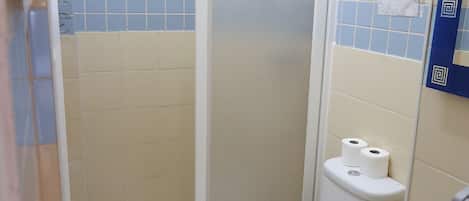A small, compact bathroom with a toilet, a sink, and a shower stall.