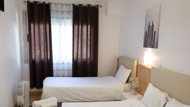 A hotel room with two beds, a heater, a lamp, and a painting on the wall. - Lisbon Suite Home (Lisbon)