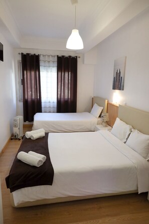 Een hotelkamer met twee bedden, een verwarming, een lamp en een schilderij aan de muur.