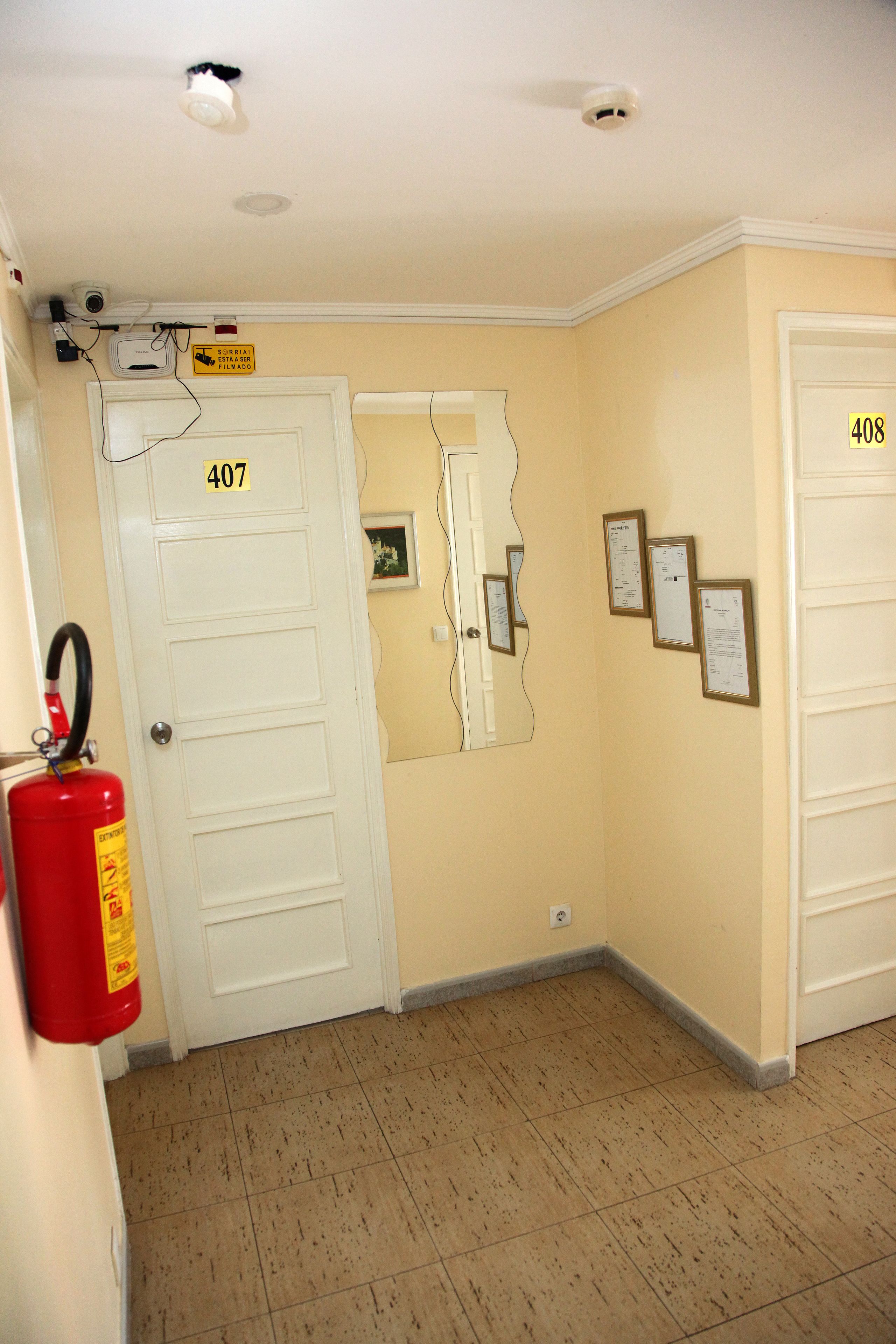 A hallway with doors numbered 407 and 408, a fire extinguisher, and wall-mounted notices.