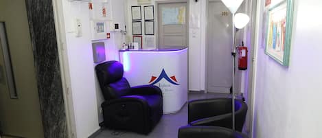 A reception area with a counter, black leather chairs, a water dispenser, and a fire extinguisher.