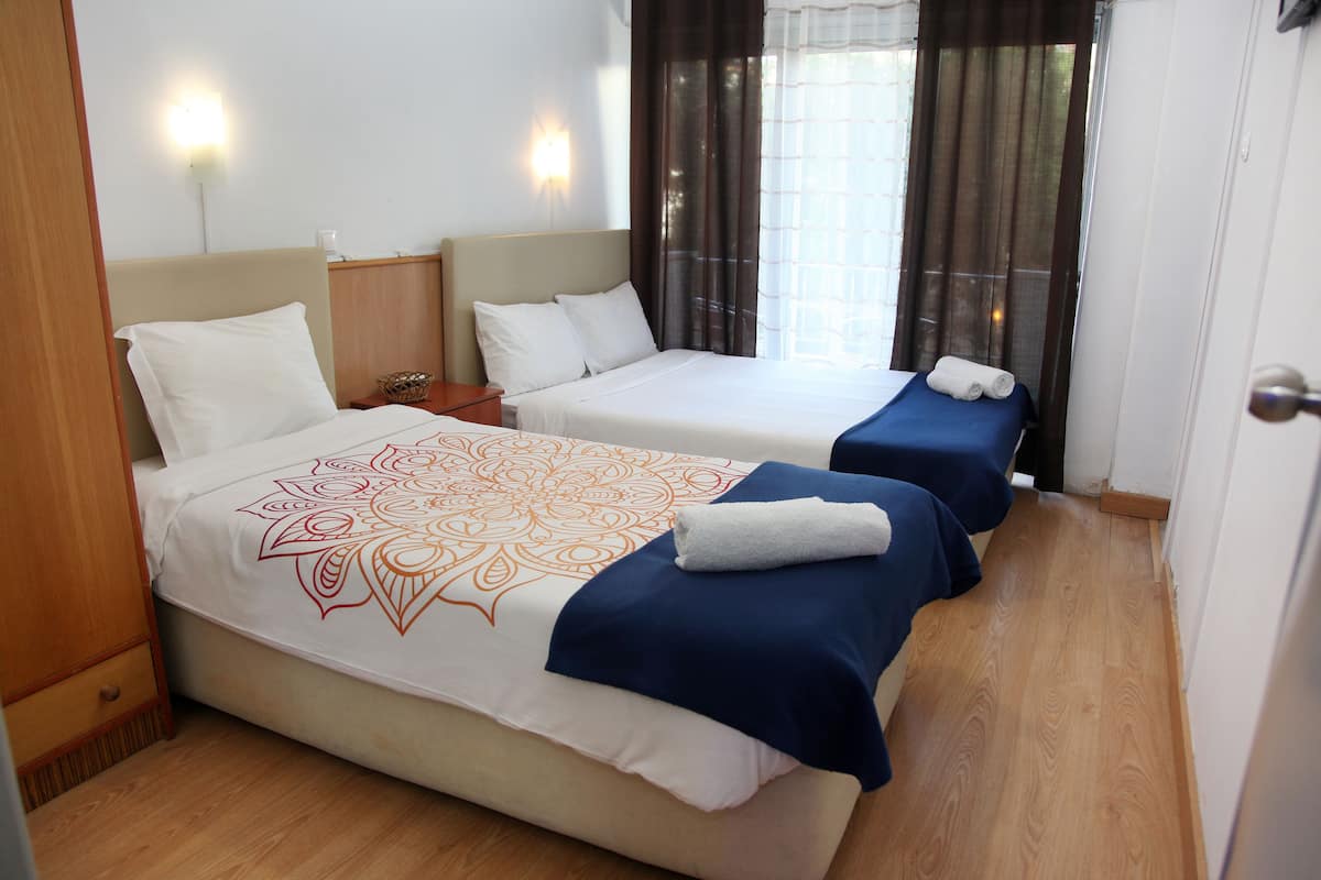 Une chambre d’hôtel avec deux lits, chacun recouvert d’une couvre-lit bleue et blanche, et dotée d’un plancher en bois.