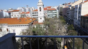 A cityscape with a prominent white building featuring a bell tower, surrounded by other buildings with red-tiled roofs. - Lisbon Suite Home (Lisbon)