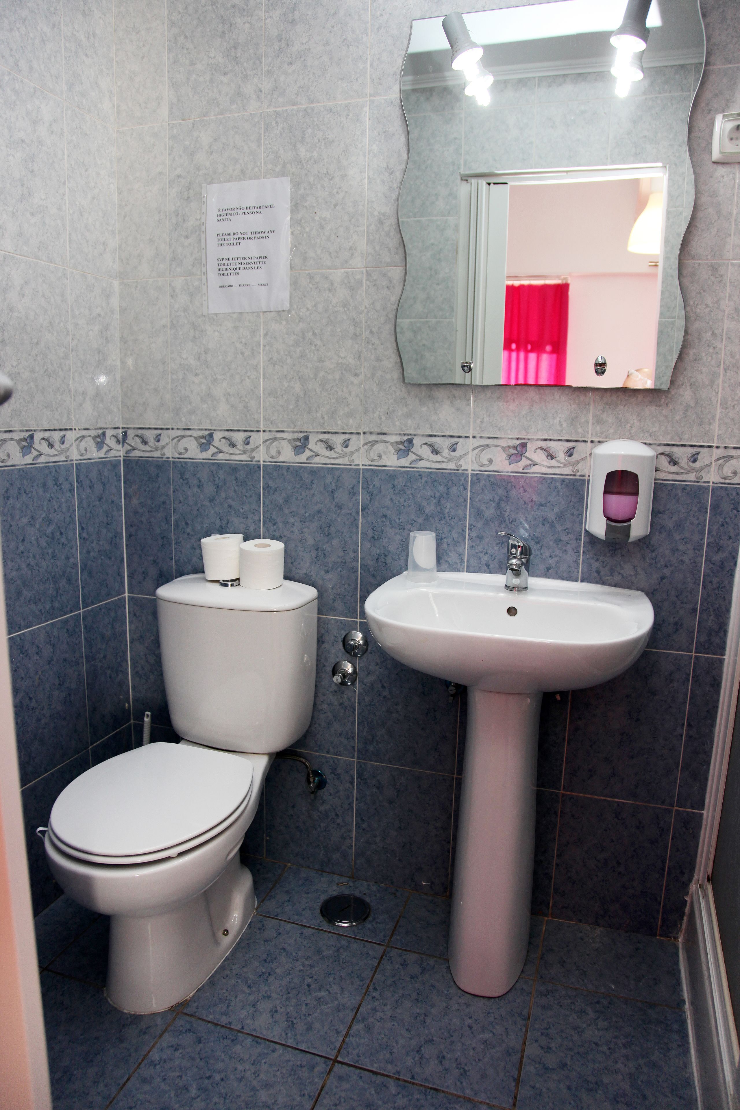 A bathroom with a toilet, sink, and mirror.