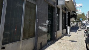 A building with a closed storefront, a visible balcony, and a cobblestone street. - Lisbon Suite Home (Lisbon)