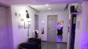 A reception area with a reception desk, two black chairs, a clock, and a door labeled "104". - Lisbon Suite Home (Lisbon)