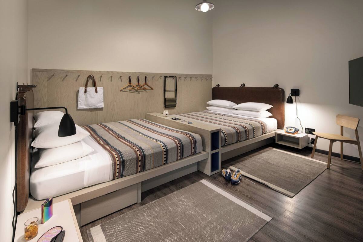 Ein modernes Hotelzimmer mit Bett, Nachttisch, Lampe und einer kleinen Sitzecke.