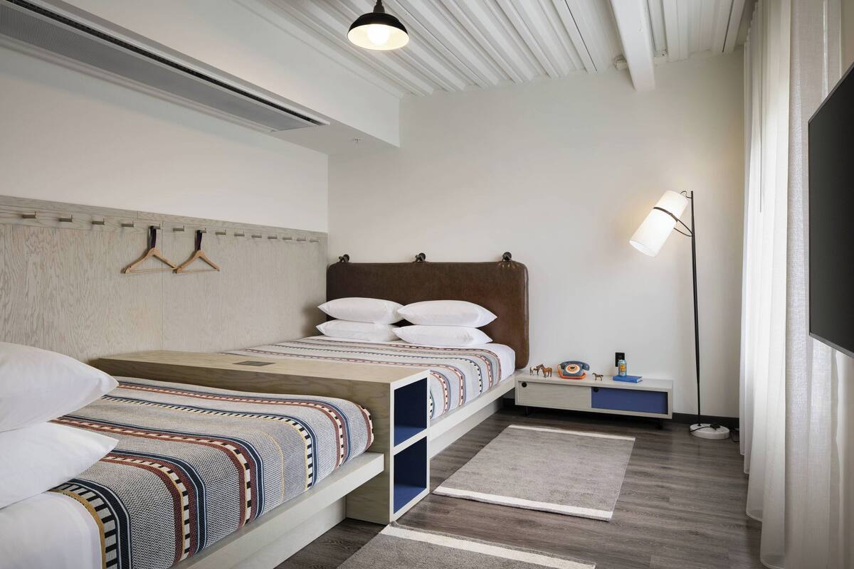 Ein modernes Schlafzimmer mit Bett, Nachttischen, einer Stehlampe und einer eingebauten Sitzbank.