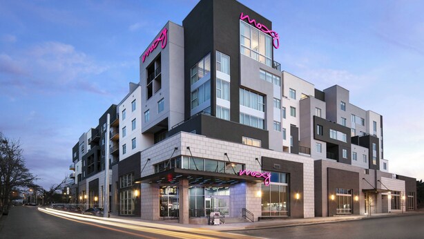 A multi-story hotel with a modern design, featuring a prominent neon sign, large windows, and a covered entrance area. - Moxy Nashville Vanderbilt Area (Nashville)