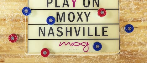 A sign with the text "PLAY ON MOXY NASHVILLE" and "MOXY HOTELS" on a wooden background.