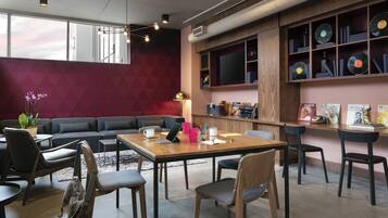 Un espacio lounge moderno con un sofá, sillas, una mesa de madera y un estante para discos.