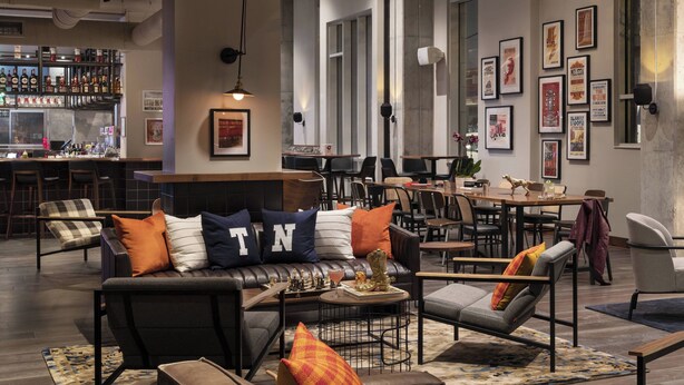 Un área de lounge moderna con bar, asientos y obras de arte en las paredes.