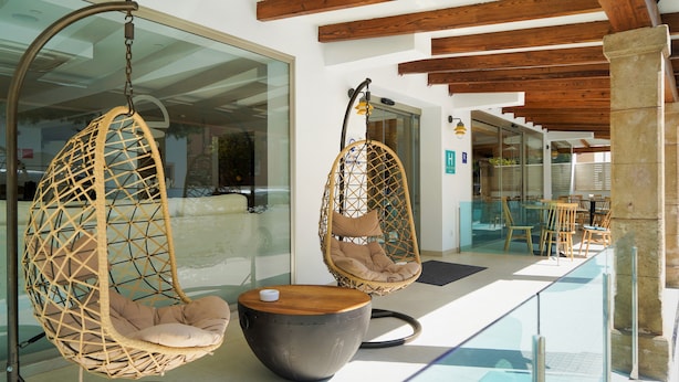 Un intérieur moderne avec deux fauteuils suspendus, une table ronde et une balustrade en verre donnant sur un espace repas.