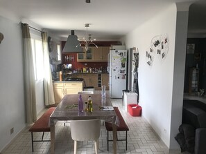 A compact kitchen with a dining table, chairs, and a refrigerator.