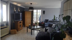 Una sala de estar con televisión, sofá, mesa de centro y comedor.