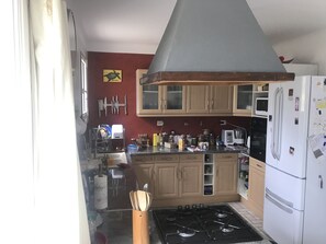 A kitchen with wooden cabinets, a gas stove, a white refrigerator, and a microwave.