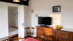 A room with a bed, a television, a wooden cabinet, and a table with chairs. - Homerez - Chalet in Métabief (Métabief)