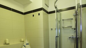 Un baño pequeño con lavadora, inodoro y ducha envuelta en vidrio.