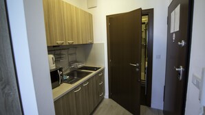 Una cocina pequeña con armarios de madera, un microondas y un lavamanos.