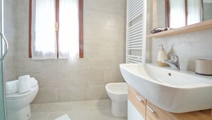 A bathroom with a toilet, bidet, and a sink with a mirror above it.